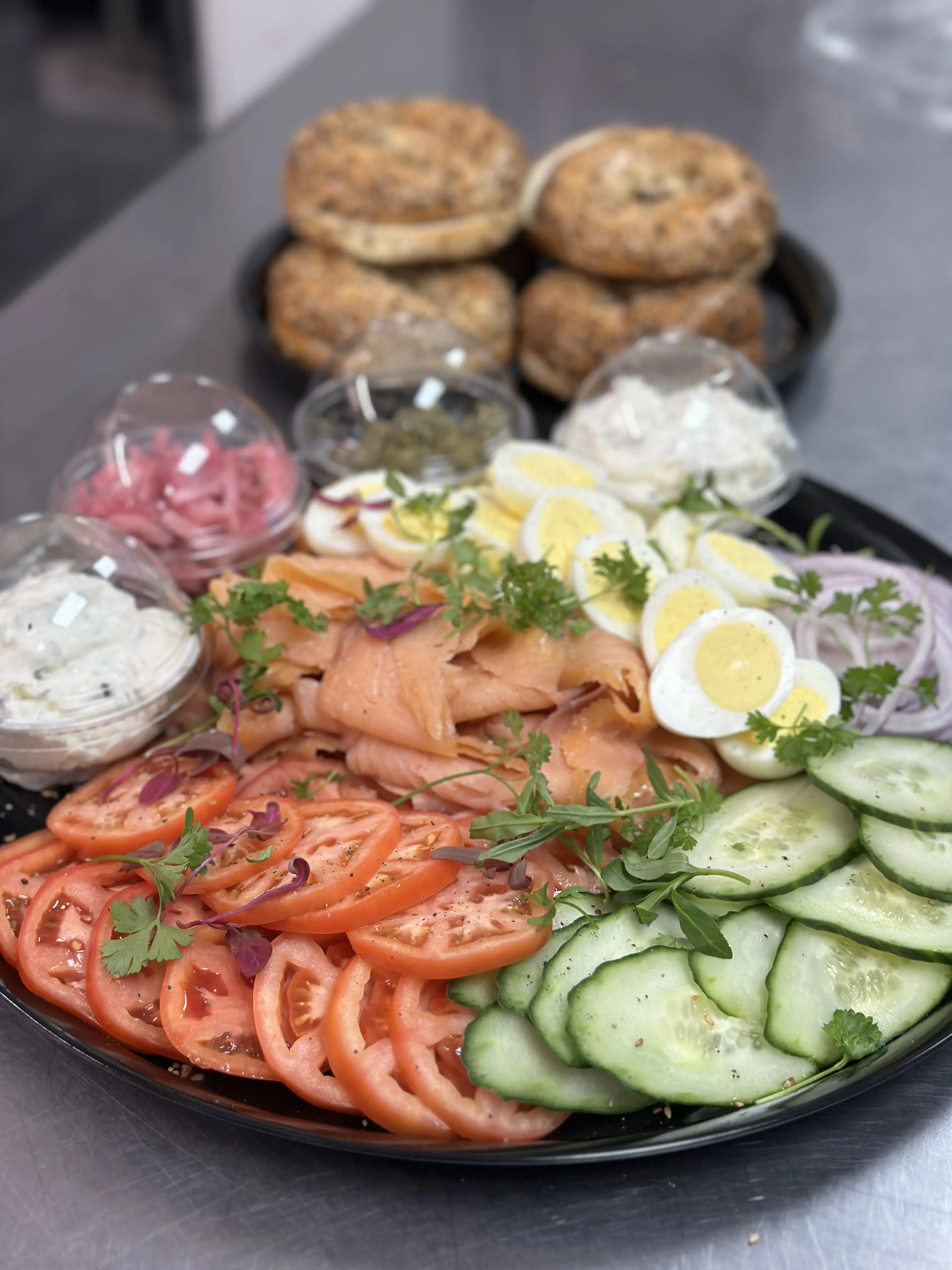 Lox catering platter with hard boiled eggs, pickled onions, tomatoes and cucumbers.